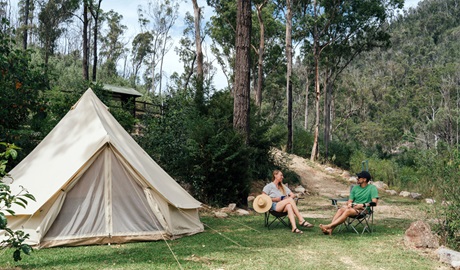 People sitting by their tent at The Junction campground, Nymboi-Binderay National Park. Photo: Jay Black &copy; DCCEEW