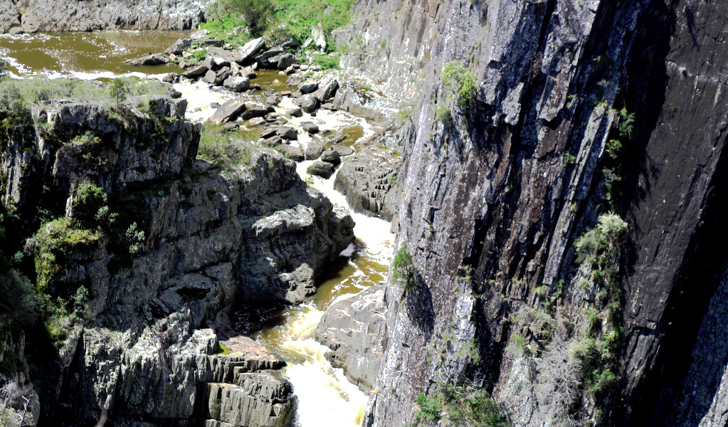 A river cascades in steps past a steep and dark slate canyon wall in Oxley Wild Rivers National Park. Photo &copy; Jessica Stokes