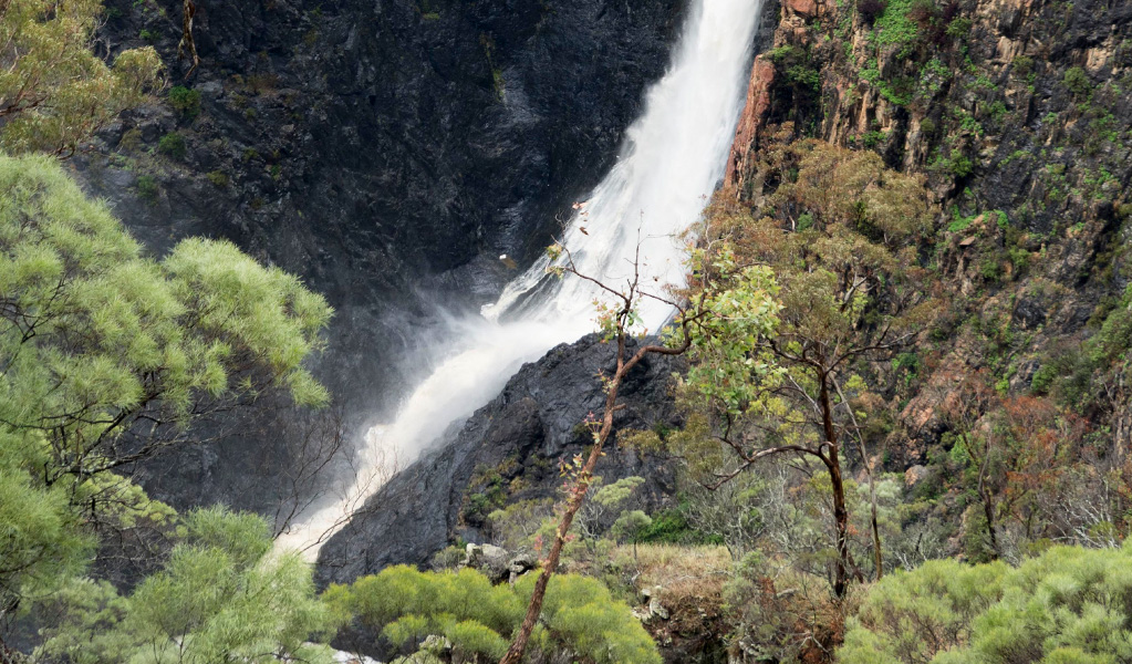 View of a waterfall cascading into a deep dark gorge. Photo credit: Leah Pippos &copy; DPIE