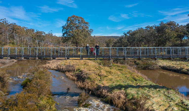3 walkers standing on a bridge over Apsley River, Oxley Wild Rivers National Park. Photo: Josh Smith &copy; DPE
