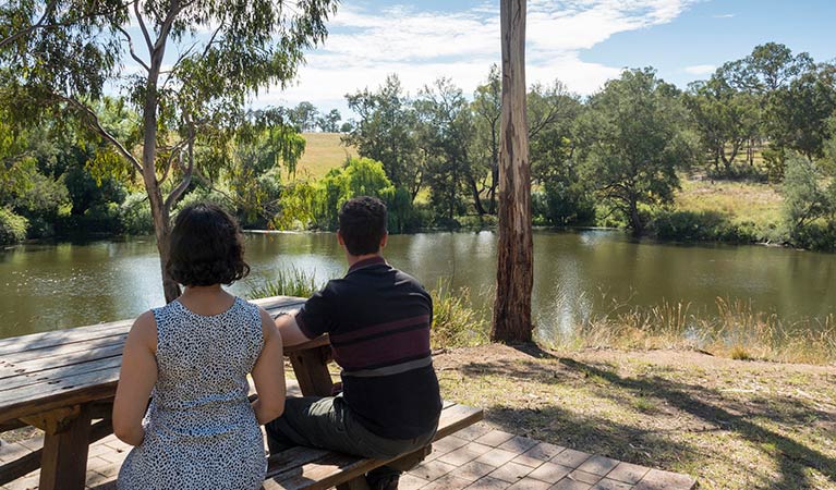 2 people resting at a picnic table at Blue Hole picnic area. Photo: Leah Pippos &copy; DPIE