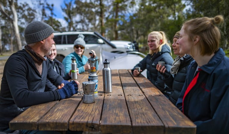 A group of friends sitting at a picnic table at Dangars Gorge campground in Oxley Wild Rivers National Park. Photo: John Smith &copy; DPE