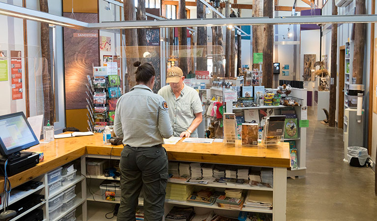 A visitor and NPWS staff member at the counter of Pilliga Forest Discovery Centre in Pilliga National Park. Photo: Leah Pippos &copy; DPIE