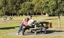 A couple enjoying the view from a picnic table at Bonnie Vale picnic area in Royal National Park. Photo: Simone Cottrell/OEH