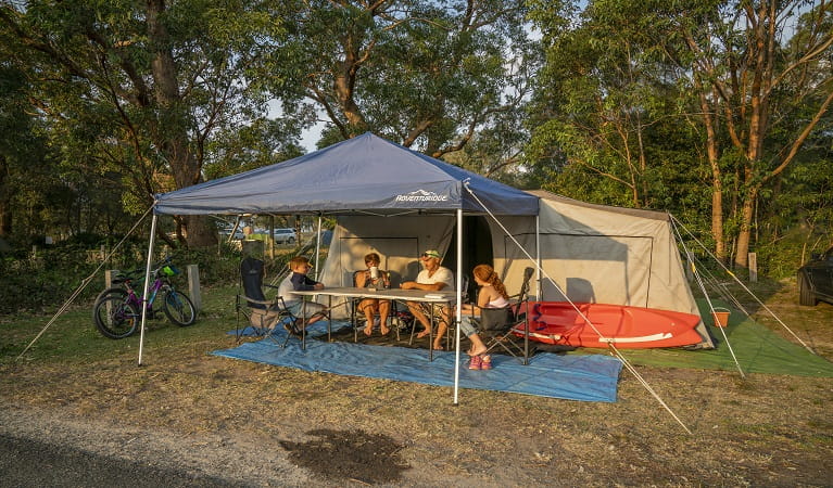 Family enjoying a drink by their tent at Bonnie Vale campground. Photo: John Spencer/OEH