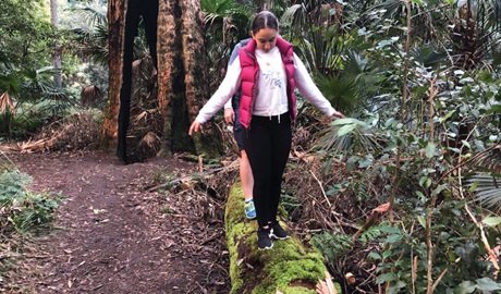 Girl walks along a mossy log in a shady forest setting. Photo: Natasha Webb