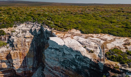 Aerial photo of a cliff with a large safety fence around a section of land to prevent visitors being injured on Wedding Cake Rock. Photo: DPIE &copy; DPIE