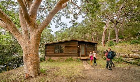 Four people walk towards Weemalah Cottage in Royal National Park. Photo: John Spencer/OEH