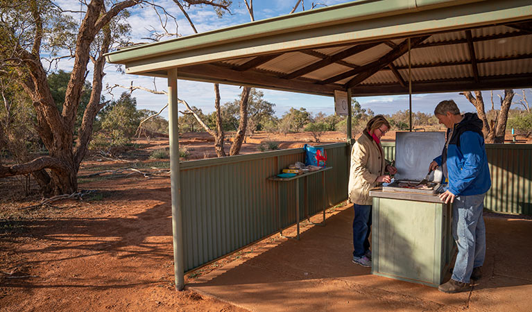 Couple cooking breakfast in the barbecue shelter at Mount Wood campground. Photo: John Spencer/DPIE