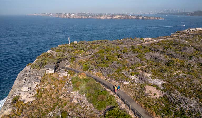 2 visitors following Fairfax walk along the coast, Sydney Harbour National Park, with the city of Sydney on the horizon. Photo: John Spencer &copy; DPE