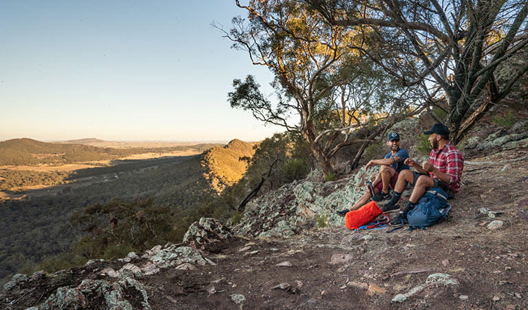 Two men sit on the ground at a viewpoint in The Rock Nature Reserve - Kengal Aboriginal Place. Photo: Robert Mulally/DPIE