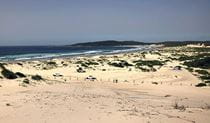 View across sand to vehicles, people, and a tent on Samurai Beach in Tomaree National Park. Photo: Jim Cutler &copy; DPIE