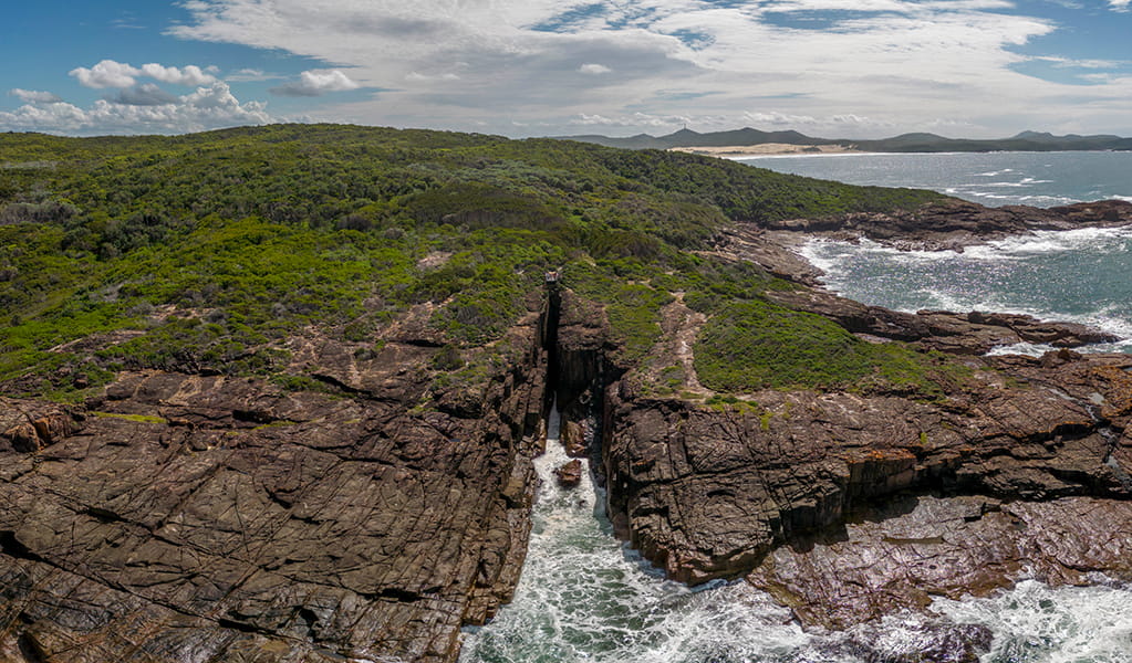 Aerial photo of Slot canyon lookout, perched over the a gap in the cliffline above the ocean. Credit: John Spencer &copy; DPE
