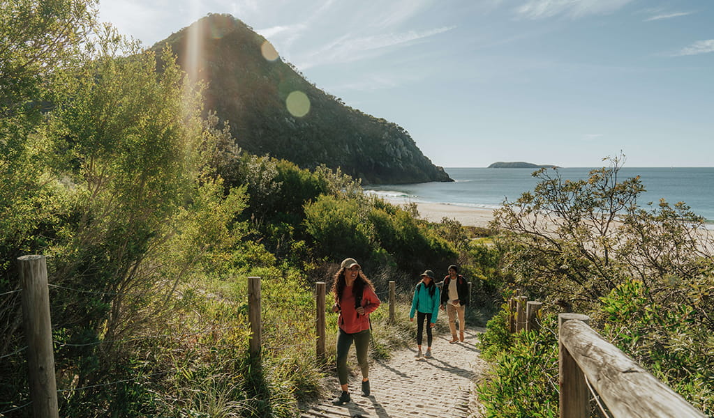 Walkers leaving Zenith Beach with Tomaree Head Summit in the background. Credit: Remy Brand © Remy Brand
