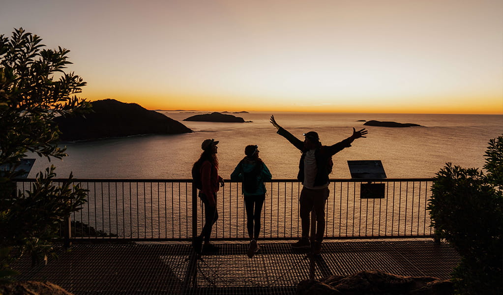 Walkers admire coastal views and islands at sunrise from the lookout at Tomeree Head Summit. Credit: Remy Brand &copy; Remy Brand