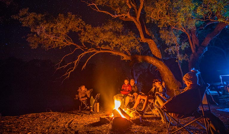 A family sit around a campfire at Darling River campground, Toorale National Park. Photo: Joshua Smith/OEH