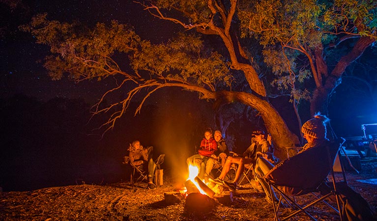 A family sit around a campfire at Darling River campground, Toorale National Park. Photo: Joshua Smith/OEH