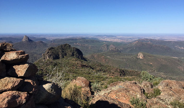 View past a rocky ledge to distant peaks, domes and plains at Bluff Mountain lookout in Warrumbungle National Park. Photo: May Fleming &copy; May Fleming