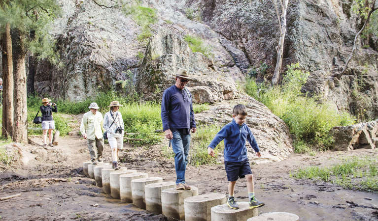 A family walking on stepping stones along Burbie Canyon walking track in Warrumbungle National Park. Photo: Simone Cottrell &copy; OEH and photographer