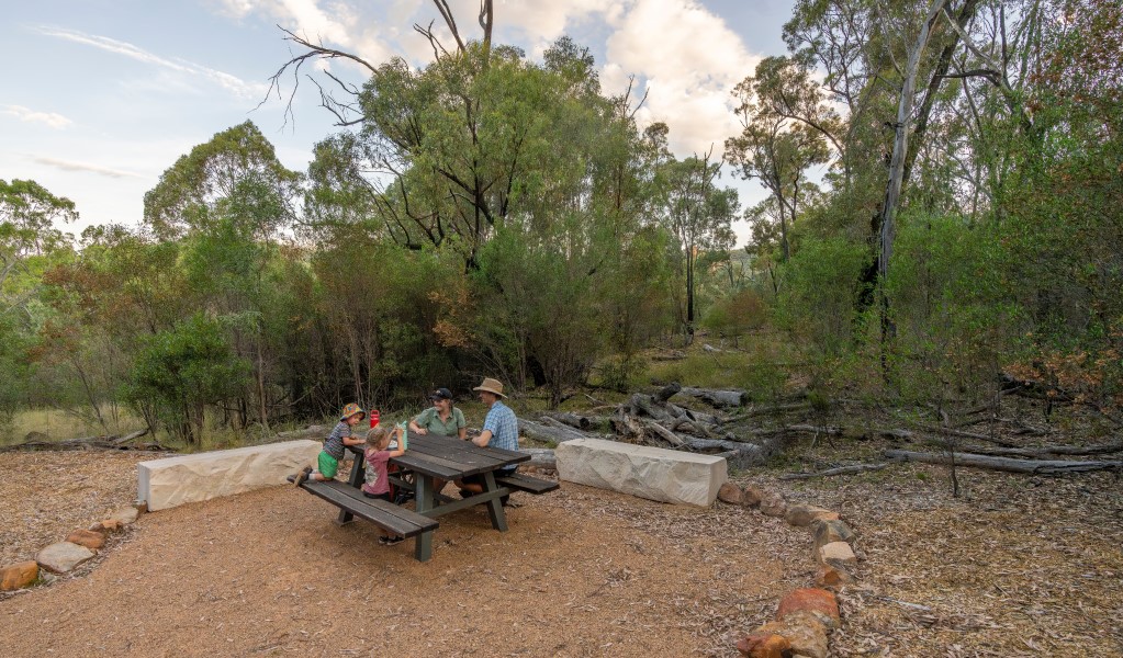 A family at a picnic table at Fans Horizon walking track in Warrumbungle National Park. Photo: John Spencer &copy; DCCEEW