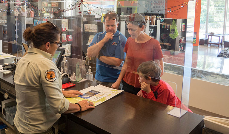 Warrumbungle Visitor Centre staff assist a family with maps and directions. Photo: Leah Pippos &copy; DPIE