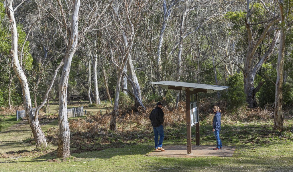 2 people reading the interpretive signage at Mooraback campground, Werrikimbe National Park. Photo: Josh Smith &copy; DPE