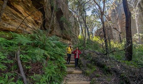 2 hikers looking up at sheer cliffs on the Glow Worm Tunnel via Wolgan Valley loop, Wollemi National Park. Credit: John Spencer &copy; DCCEEW