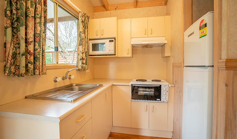Kitchen with fridge, microwave, stove-top oven and sink in one of the Wombeyan Caves cabins. Photo: OEH/John Spencer