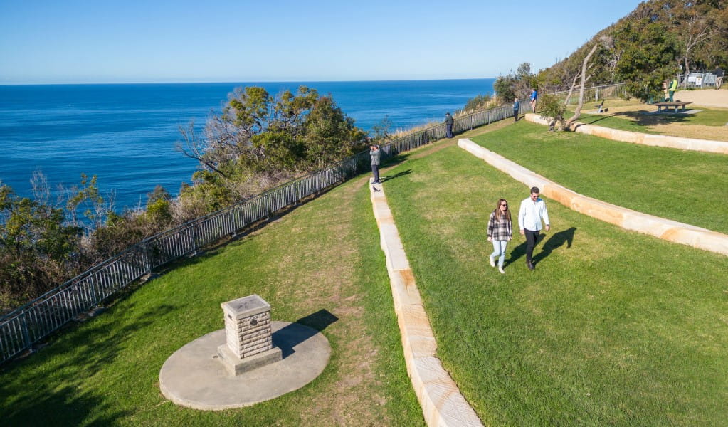 A couple walking along one of the grassy tiers at Crackneck Point lookout in Wyrrabalong National Park. Photo: John Spencer &copy; DPE