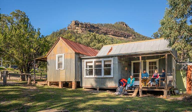 A group of friends relaxing on the verandah of Slippery Norris Cottage in Yerranderie Regional Park. Photo: John Spencer/OEH