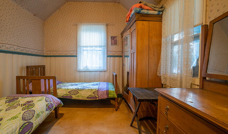 A bedroom with two single beds, a wardrobe and chest of drawers at Slippery Norris Cottage in Yerranderie Regional Park. Photo: John Spencer/OEH