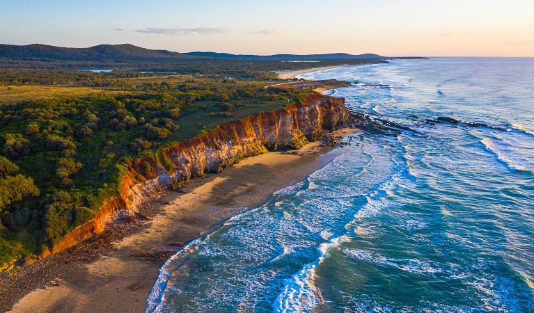 An aerial view of the red cliffs and ocean at Red Cliff campground in Yuraygir National Park. Photo: Jessica Robertson &copy; DCCEEW