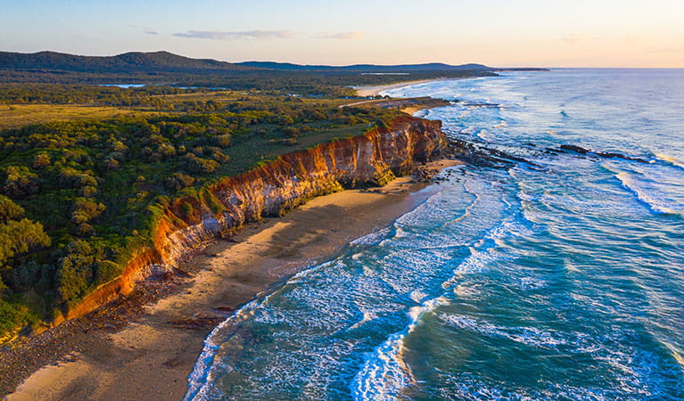 Aerial shot of the red cliffs at Lake Arragan and Red Cliff campgrounds in Yuraygir National Park. Photo: Jessica Robertson &copy; DPIE