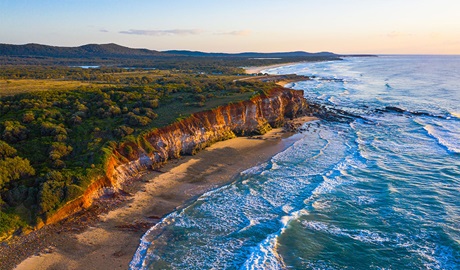 Aerial shot of the red cliffs at Lake Arragan and Red Cliff campgrounds in Yuraygir National Park. Photo: Jessica Robertson &copy; DPIE