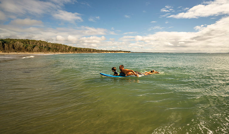 A father and young son swim on a paddle board in Bundjalung National Park. Photo: John Spencer/OEH