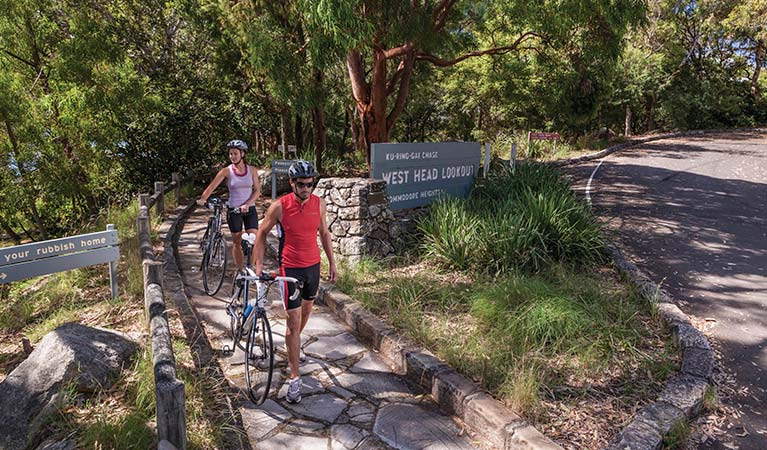 Cyclists walking their bikes on the path to West Head lookout in Ku-ring-gai Chase National Park. Photo: David Finnegan/DPIE