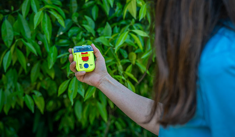 Walker holding a Personal Locator Beacon (PLB). Photo: John Spencer/DPIE