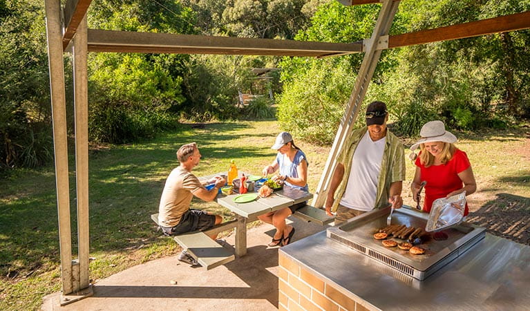 Campers cooking sausages on an NPWS-installed electric barbecue at Putty Beach campground. Photo: John Spencer/DPIE
