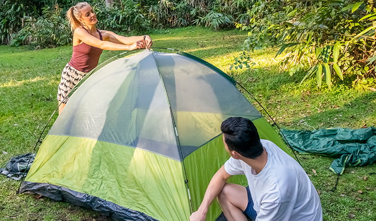 2 campers setting up a tent on the grass. Photo: John Spencer/DPIE