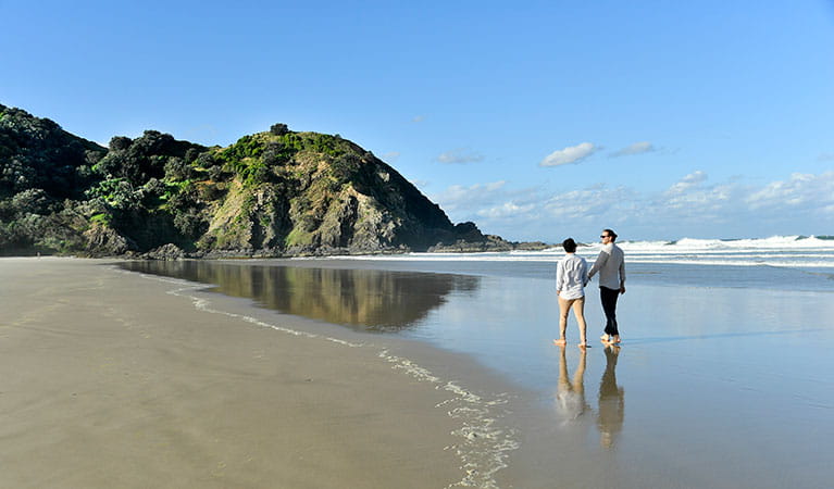 A couple walking along the sand at Tallow Beach in Cape Byron State Conservation Area. Photo: Fiora Sacco &copy; DPIE
