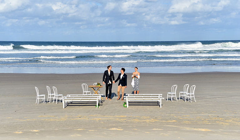 A couple and their celebrant with the ocean in the background at Cosy Corner at Tallow Beach. Photo: Fiora Sacco &copy; DPIE