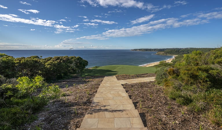 View of paved path leading to the lawn at Hickson Street lookout, with beach,  bushland and ocean in the distance.  Photo credit: John Spencer &copy; DPIE  