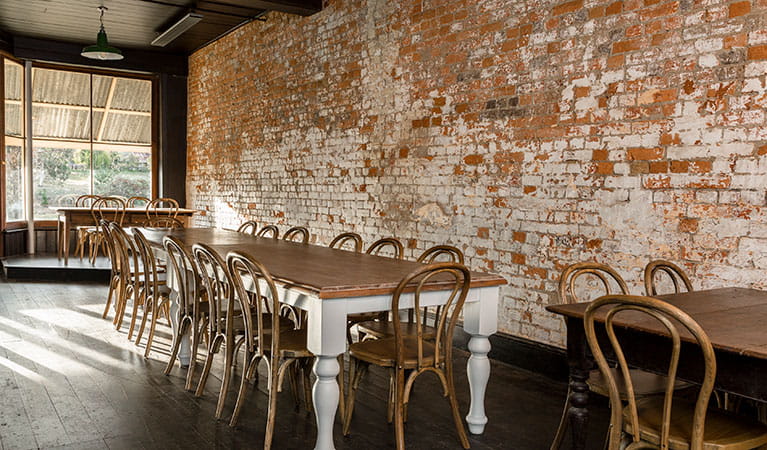 Tables and chairs inside Hosies at Hill End Historic Site with an exposed brick wall in the background. Photo: Silversalt Photography &copy; DPIE