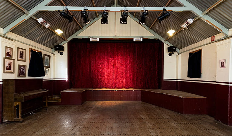 The interior of Royal Hall with the stage at the back, behind a red curtain in Hill End Historic Site. Photo: Jennifer Leahy &copy; DPE