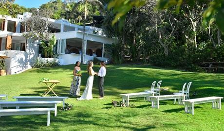 A couple and a celebrant saying their vows on Wategos lawn in Cape Byron State Conservation Area. Photo: Fiora Sacco &copy; DPIE