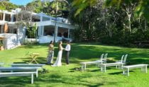 A couple and a celebrant saying their vows on Wategos lawn in Cape Byron State Conservation Area. Photo: Fiora Sacco &copy; DPIE