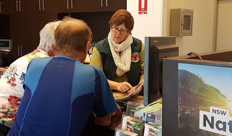 Two visitors being advised by an NPWS worker at the Warrumbungle Visitor Centre. Photo: Leah Pippos &copy; DPIE