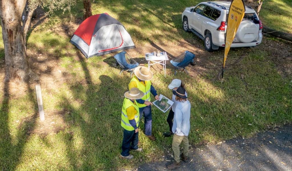 Two campground host volunteers show visitors the campground layout referring to a map, Killalea Regional Park. Credit: John Spencer/DCCEEW &copy; DCCEEW